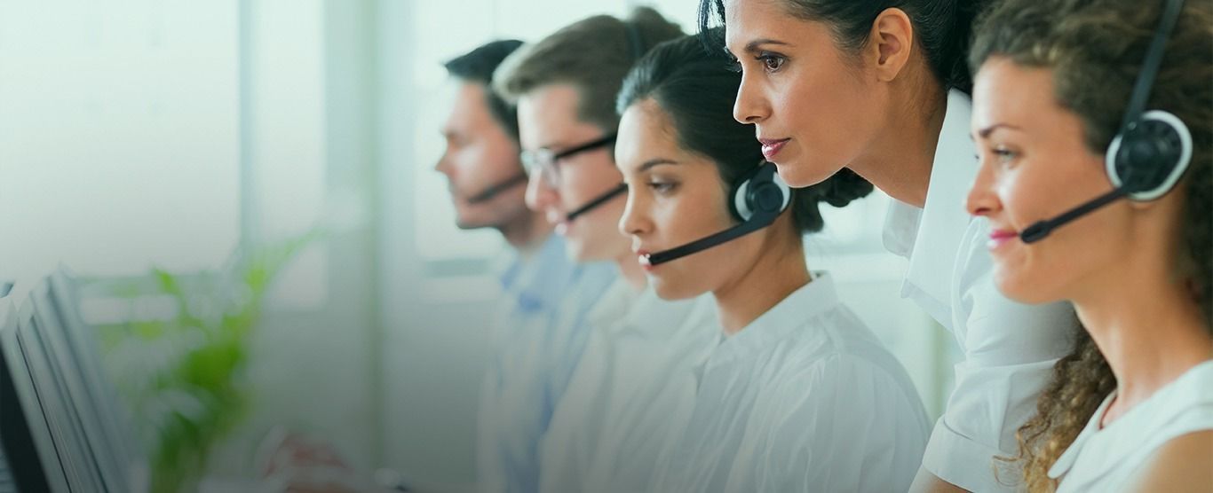 Representantes de atendimento ao cliente trabalhando em computadores e usando fones de ouvido.