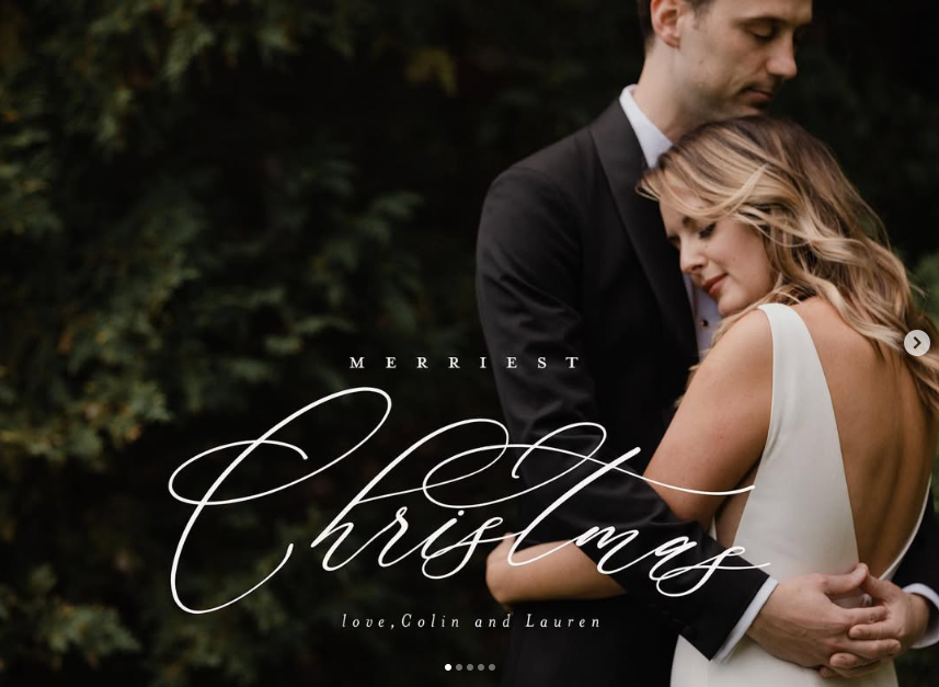 A bride and groom are hugging each other in front of a sign that says christmas.