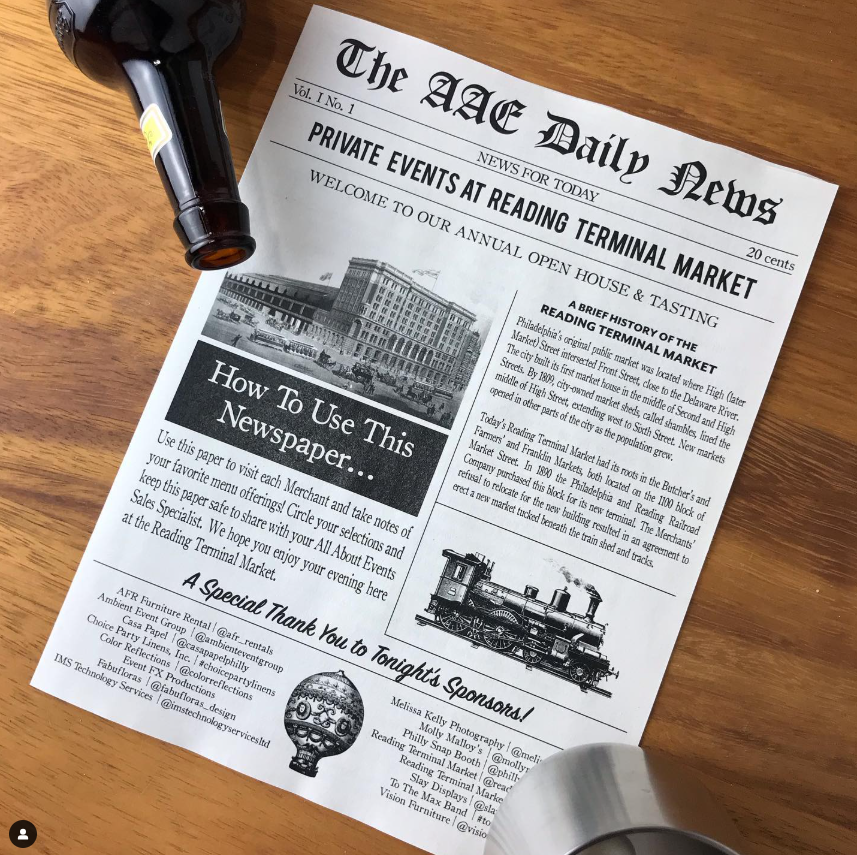 A newspaper is sitting on a wooden table next to a bottle of beer.