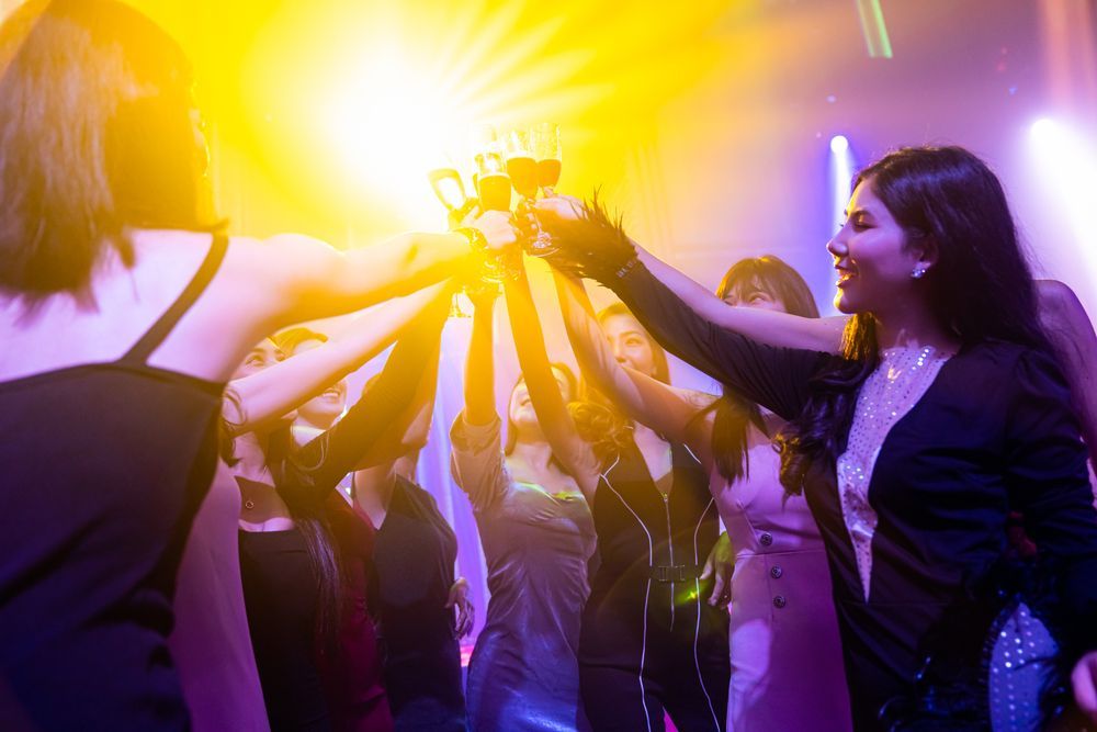 A Group Of Women Are Raising Their Glasses In The Air At A Party — HYP-E-VENTS In Spence, ACT