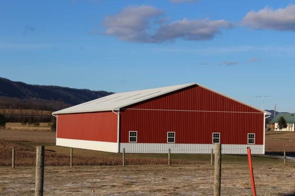 A red and white barn is in the middle of a field