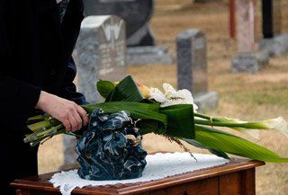 Une personne met des fleurs dans un vase sur une table dans un cimetière.
