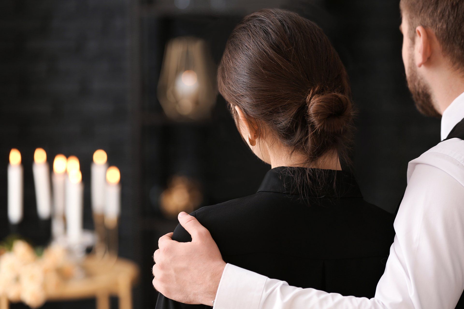 Un homme serre une femme dans ses bras lors d'un enterrement.