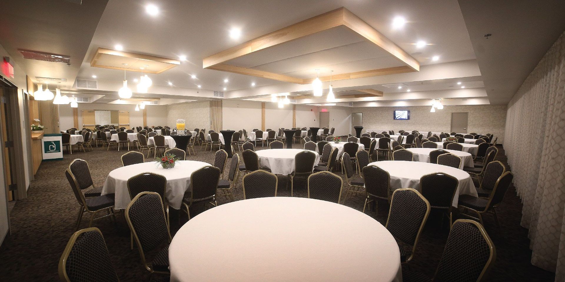 Une grande salle avec des tables et des chaises installées pour une réception de mariage.