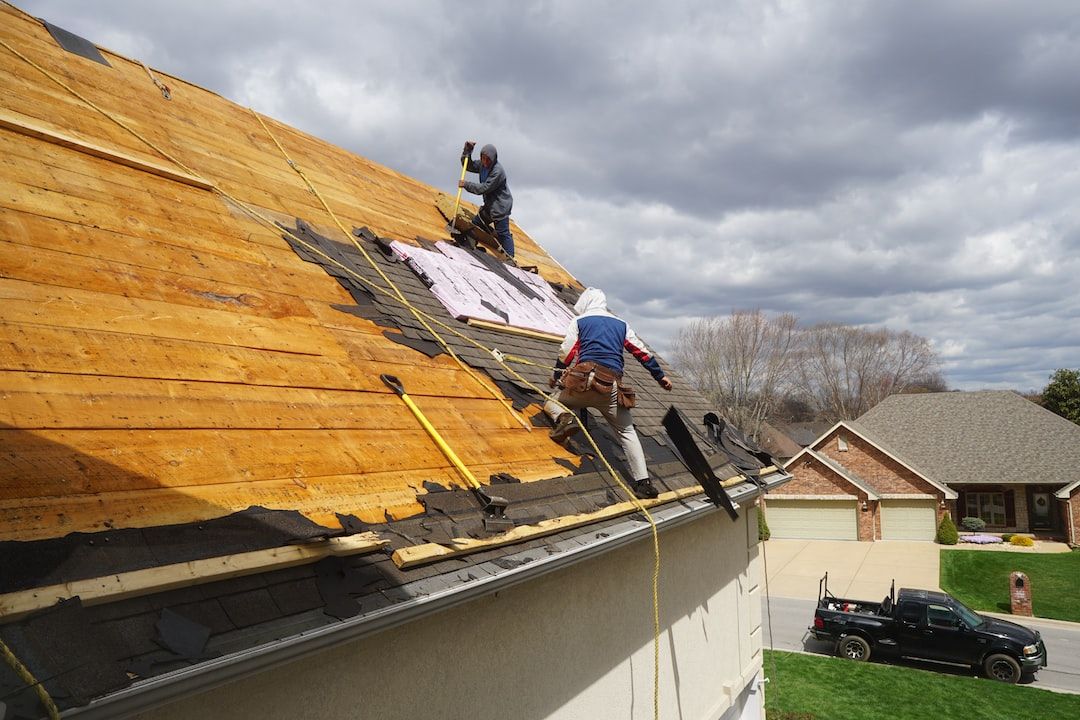 Two men are working on the roof of a house.