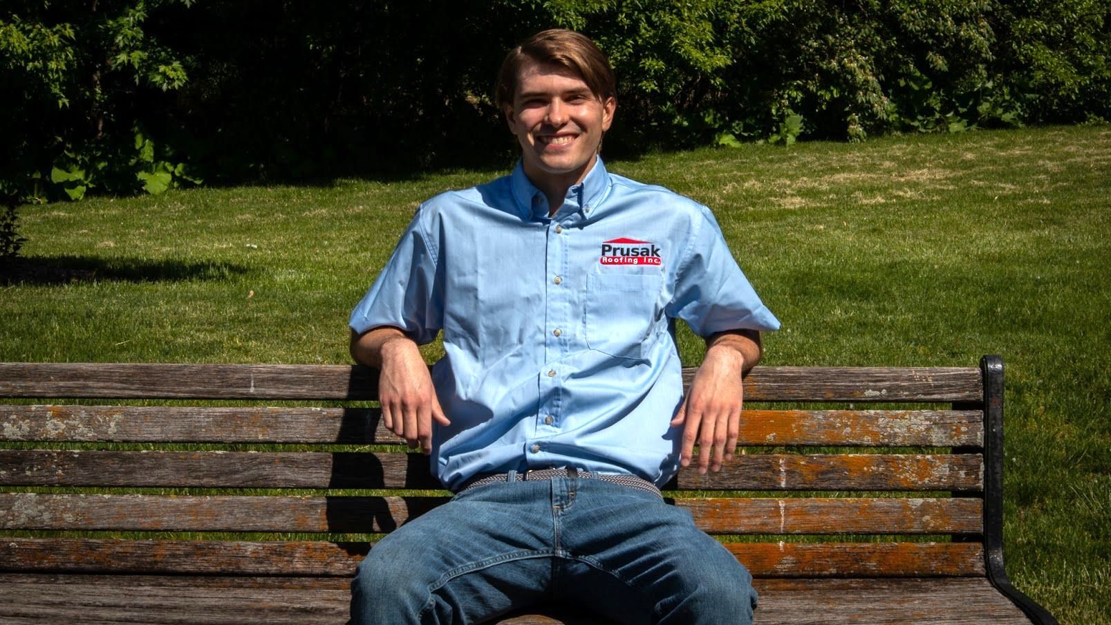 A man in a blue shirt is sitting on a park bench