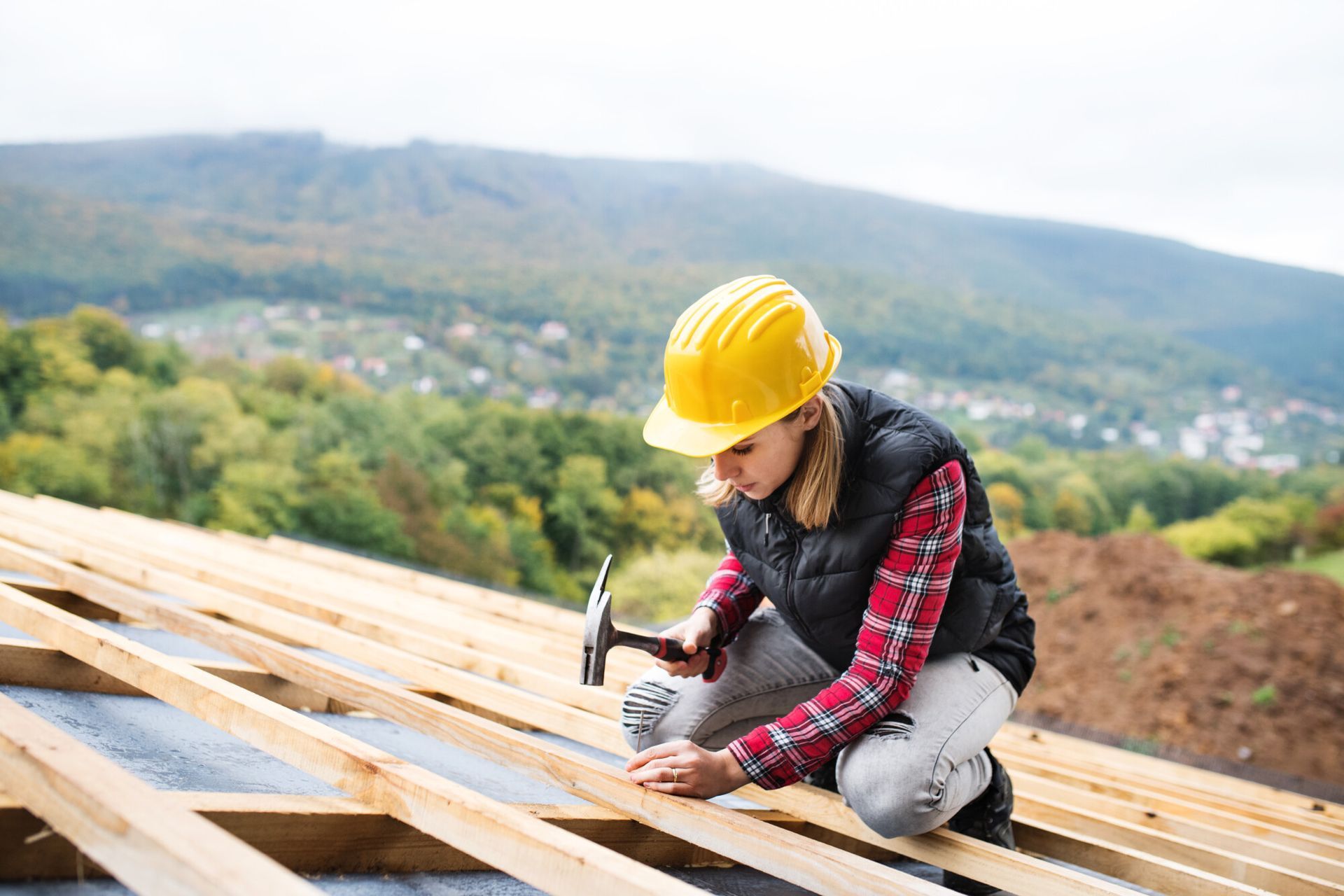 A woman is working on a wooden roof with a hammer.