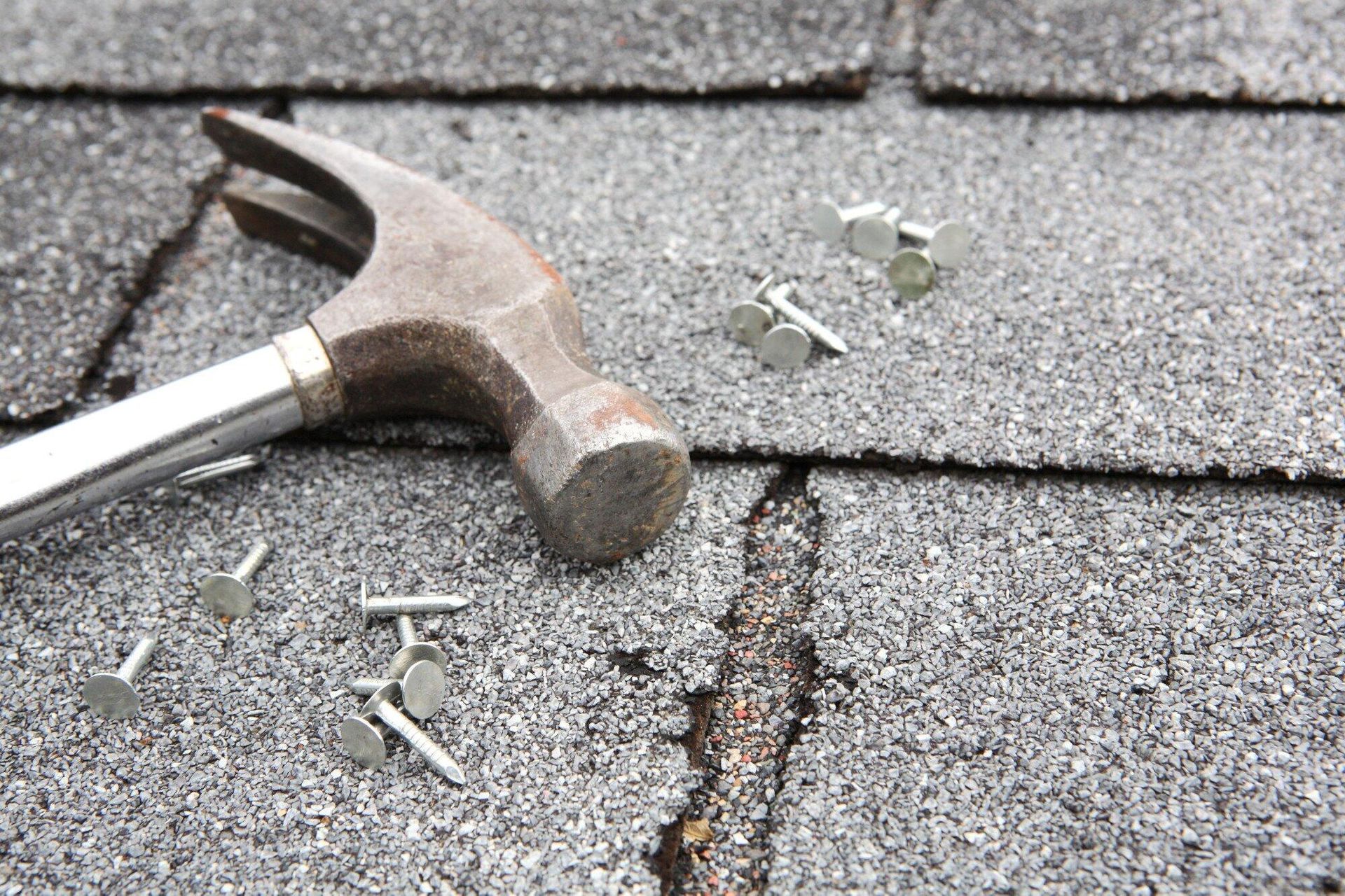 A hammer and nails are laying on a roof.