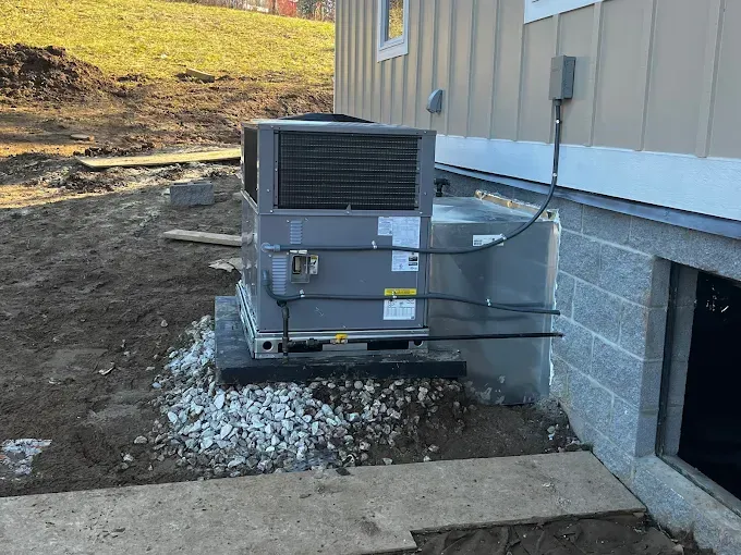HVAC unit on a concrete base next to a building. Gravel surrounds the unit.