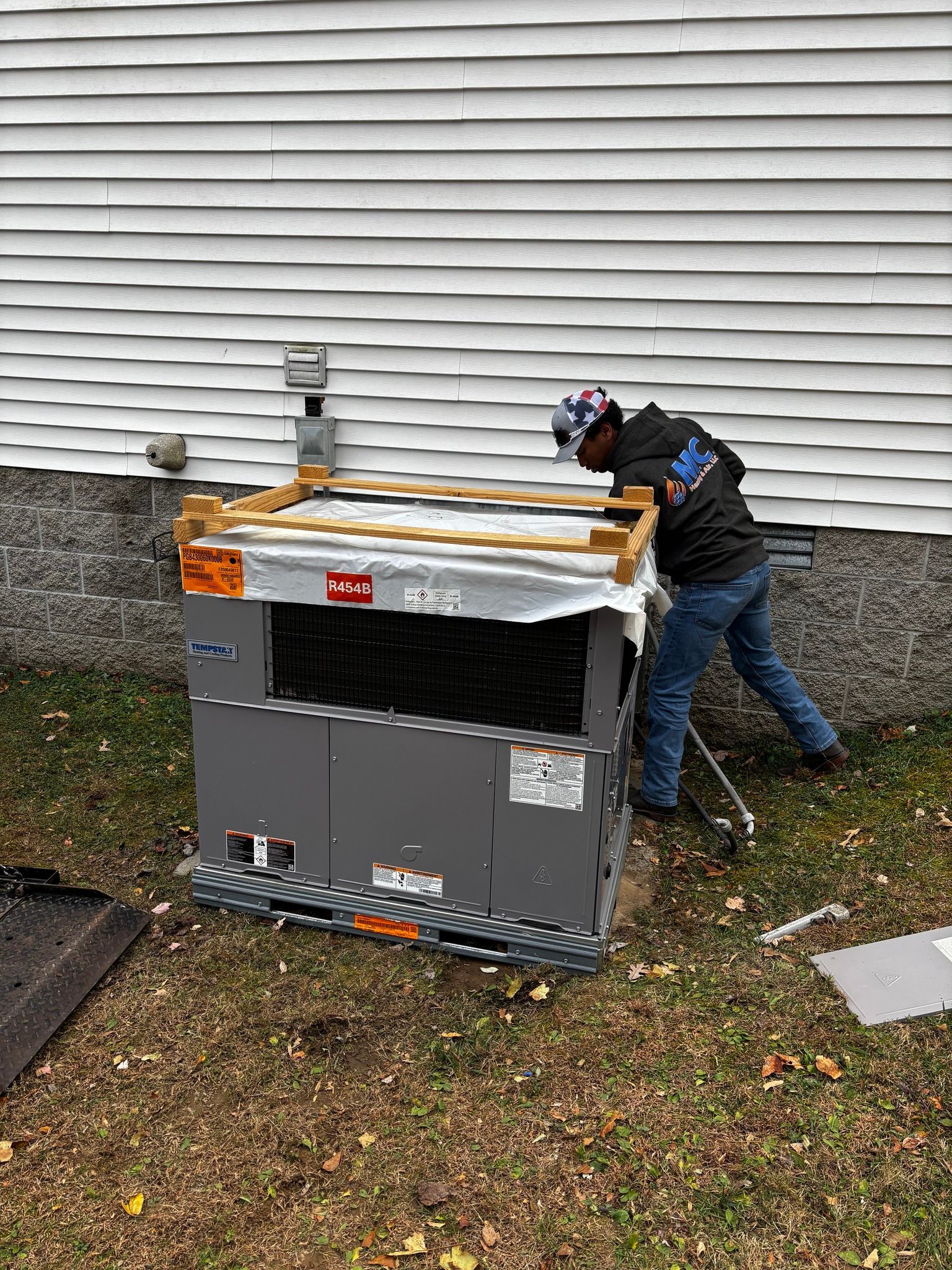 Person next to a new air conditioner unit outside a house.