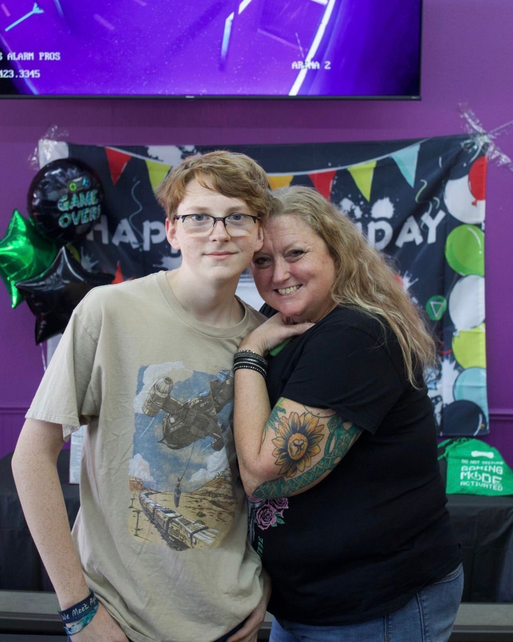 A woman and a boy are posing for a picture in front of a sign that says happy day