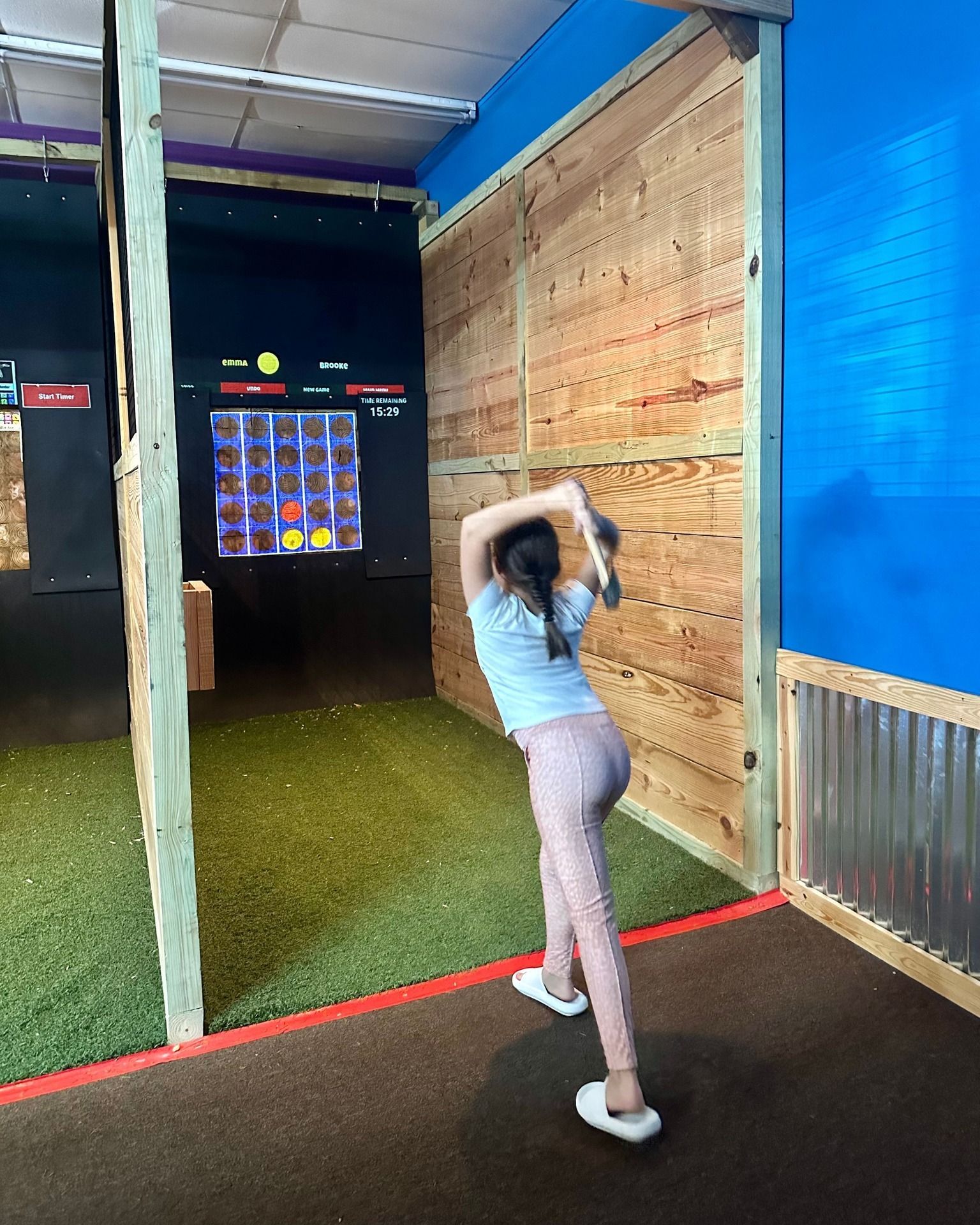 Person preparing to throw an axe at a digital target in an indoor range.