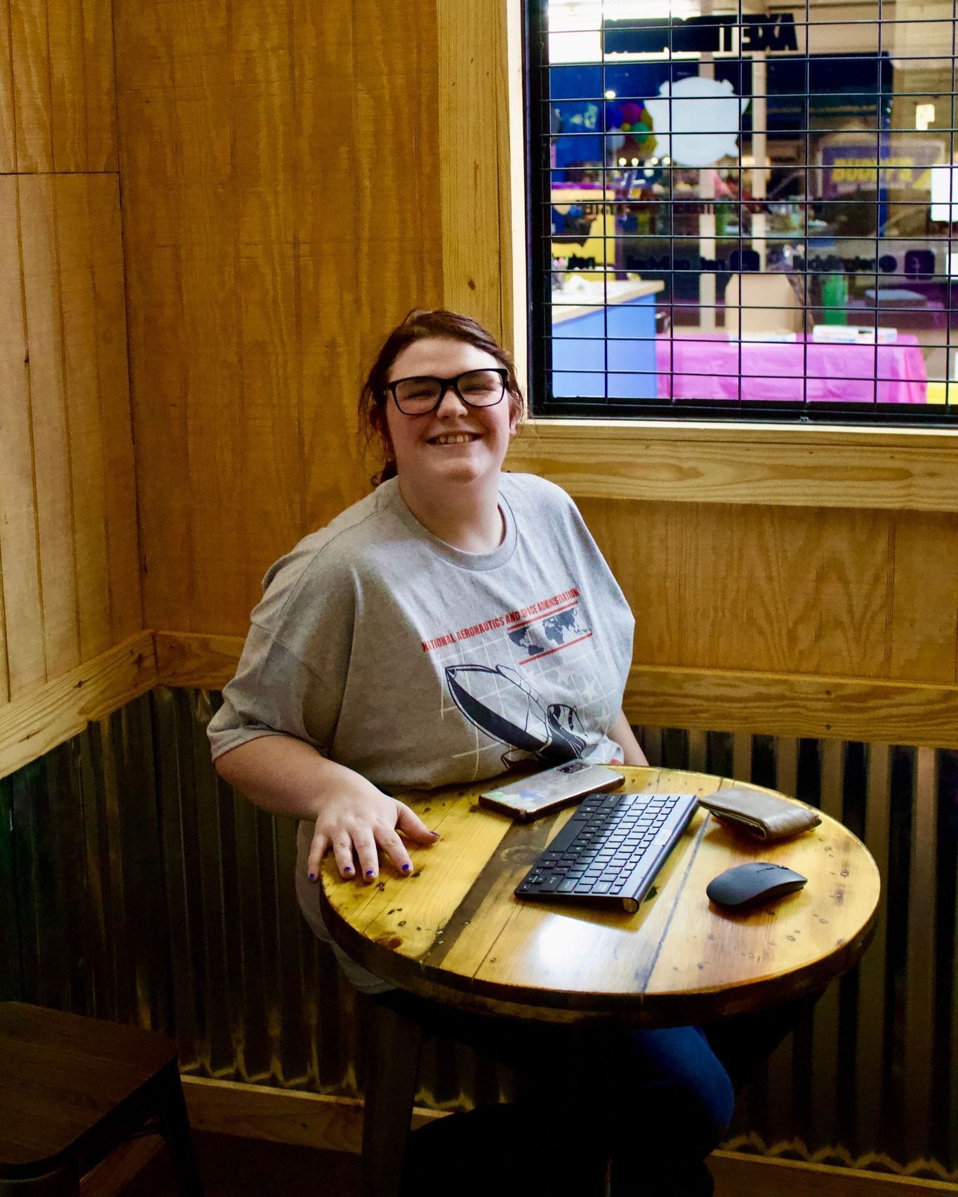 A woman is sitting at a table with a keyboard and mouse.