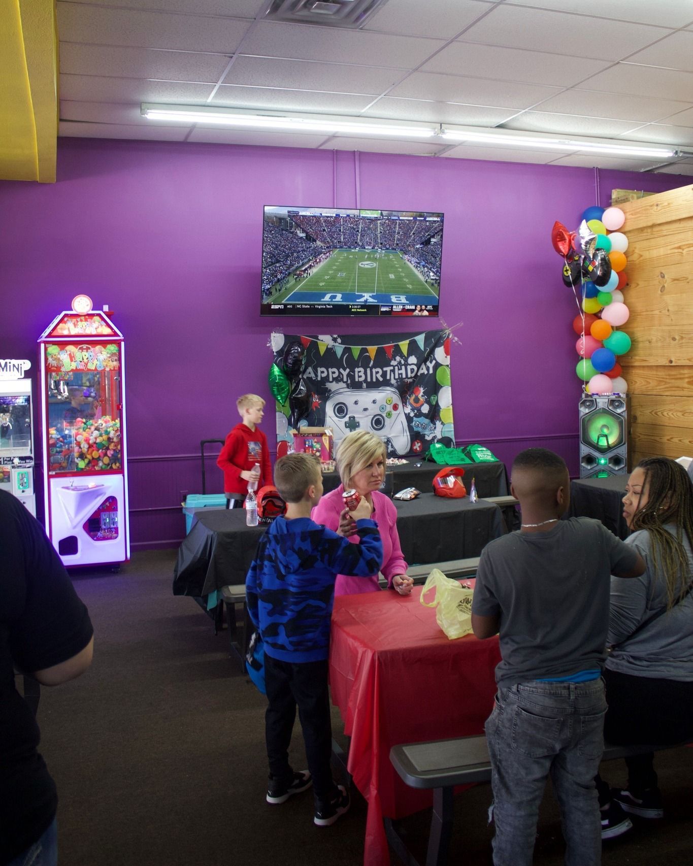 A group of children are gathered in a room with a sign that says happy birthday