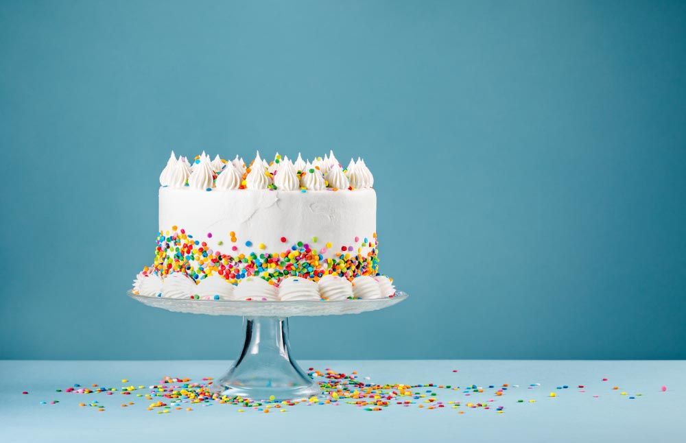 White Cake With Sprinkles Over A Blue Background