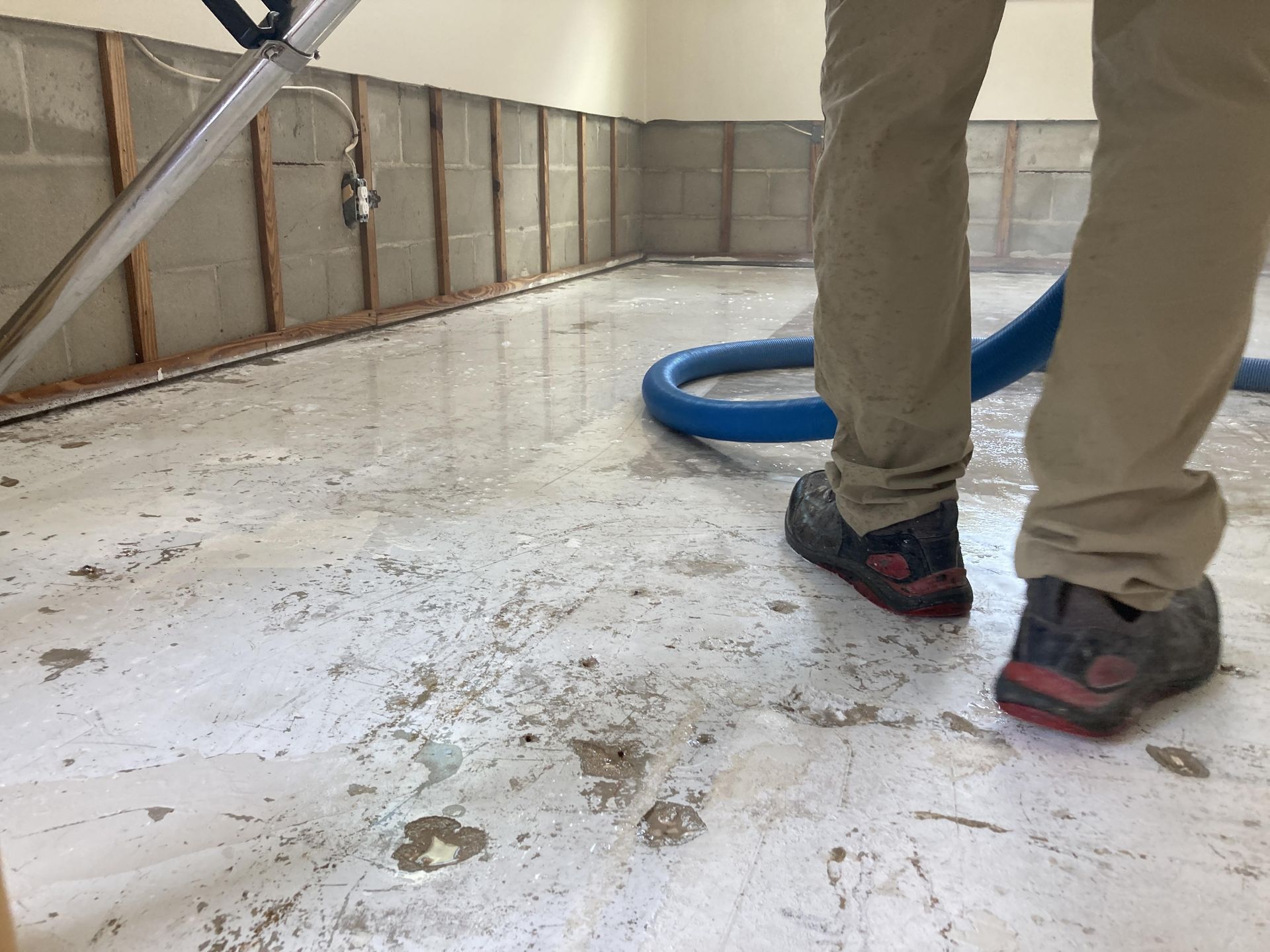 a man is using a vacuum cleaner to clean a flooded floor in a living room .