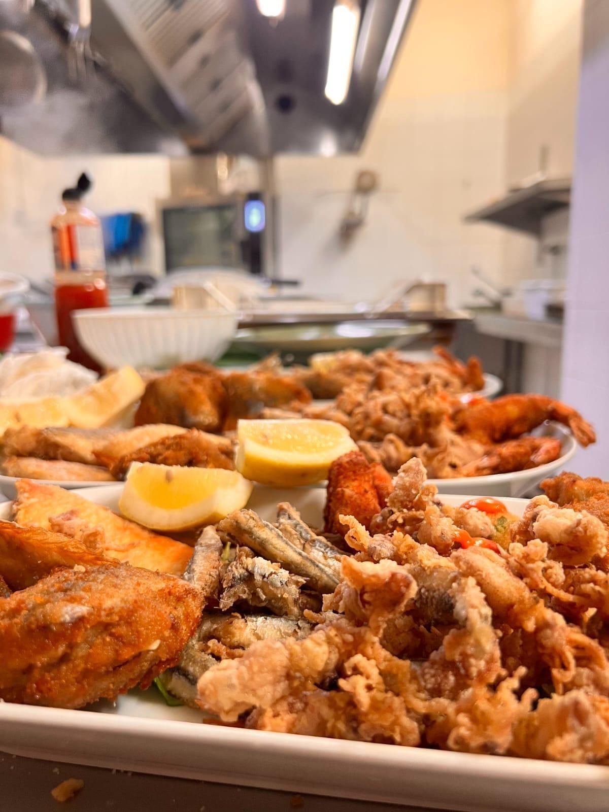 Un piatto bianco con sopra cibo fritto e fette di limone in una cucina.