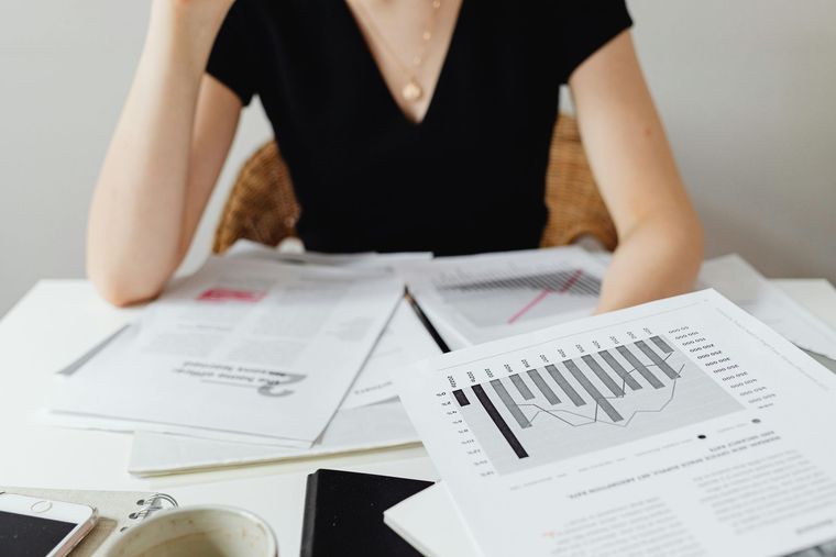 Woman at desk reviewing financial graphs and documents.