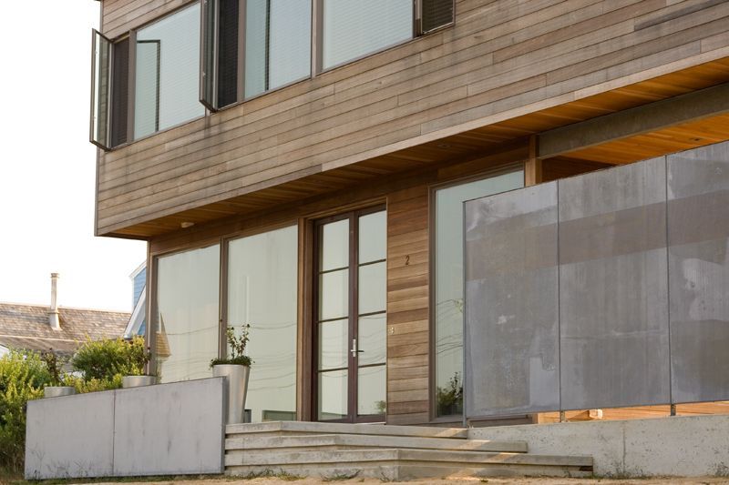 A modern beach house with wood siding, metal windows and screens 