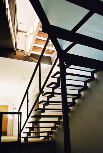 A glass staircase illuminates the wine cellar foyer below