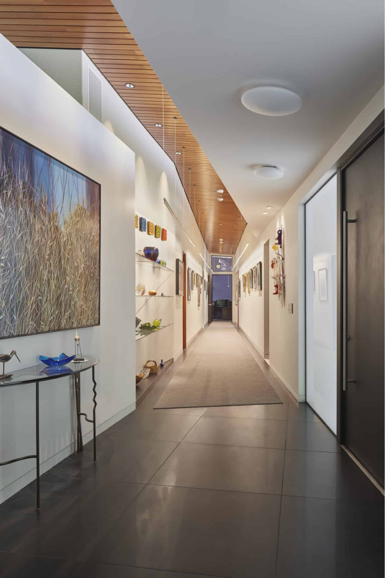 Long hallway with a wood ceiling displays art