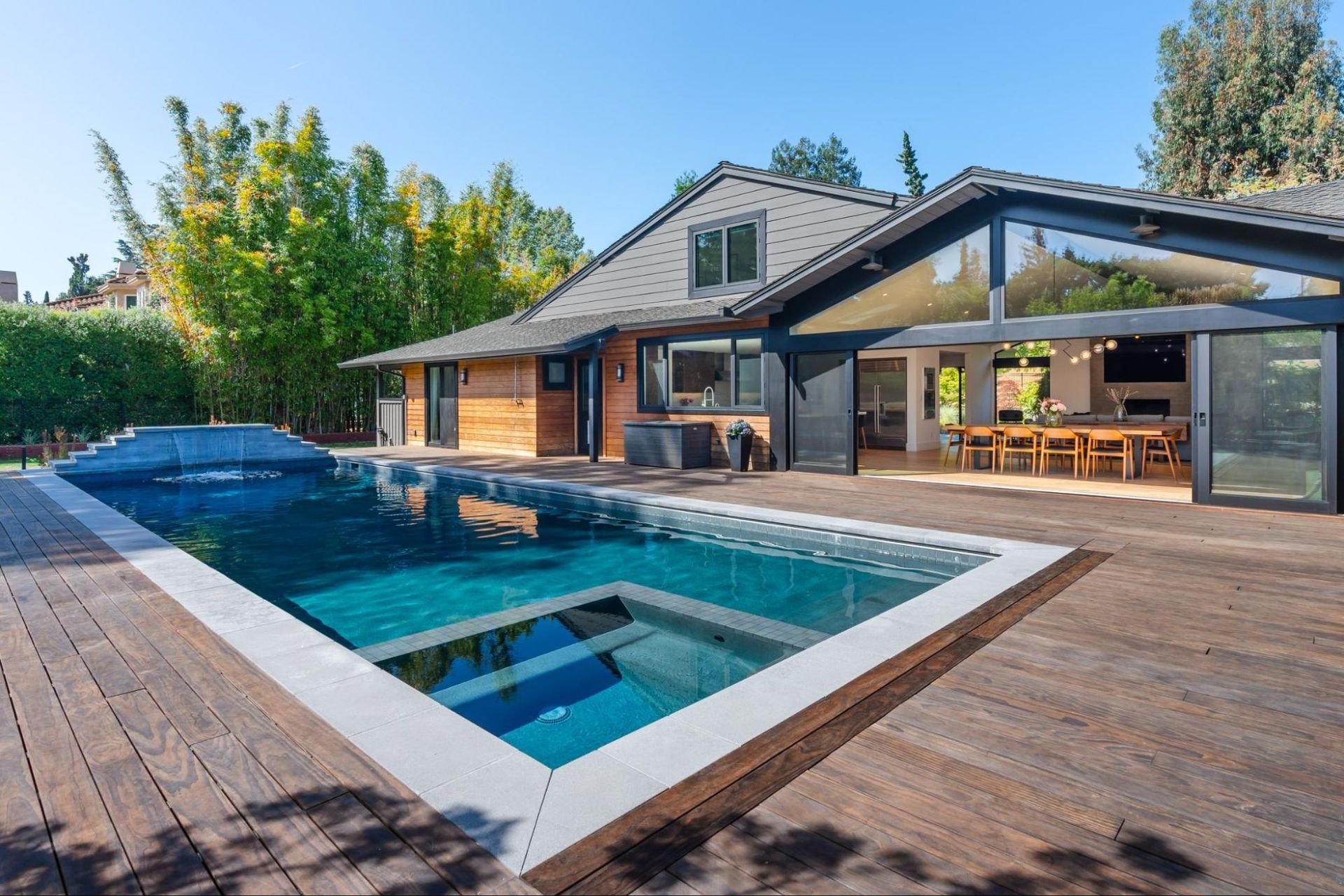 A large swimming pool is in the backyard of a house