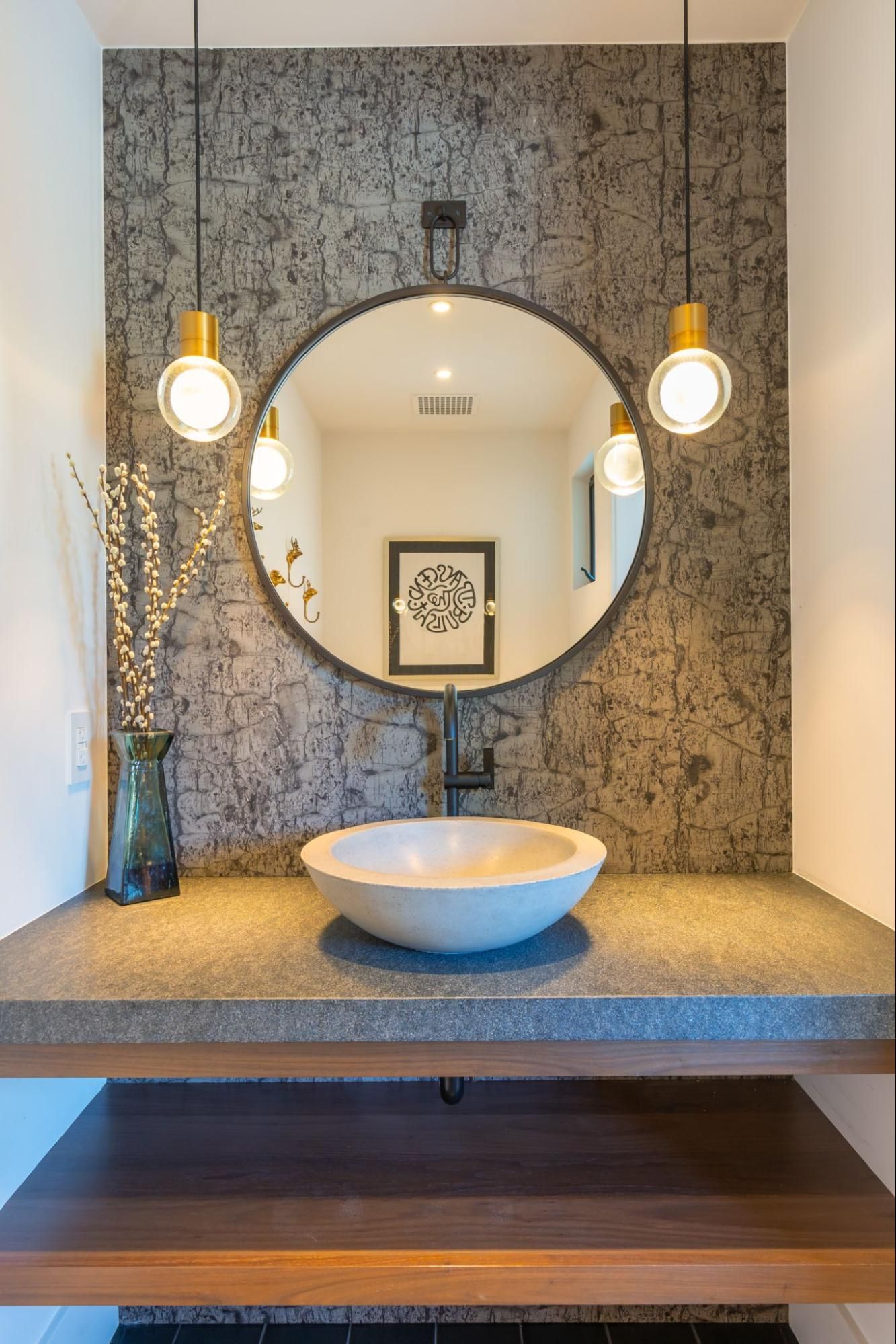 The powder room with a round sink and mirror