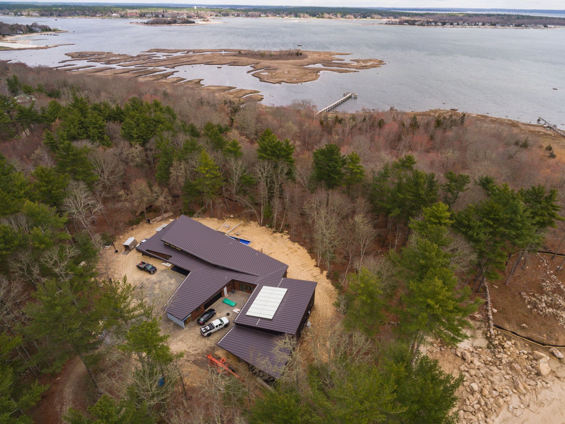 An aerial view of a house in a woodland setting next to Sippican Harbor