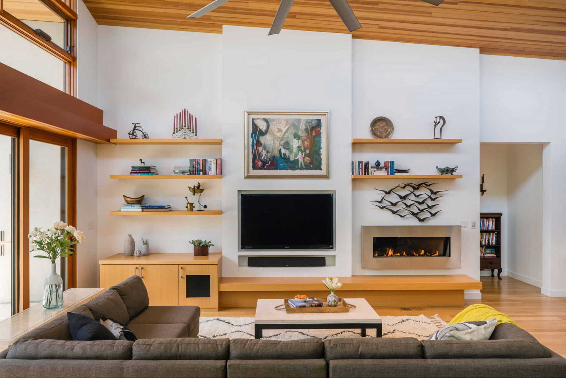 A living room with built-in cabinetry, fireplace and TV