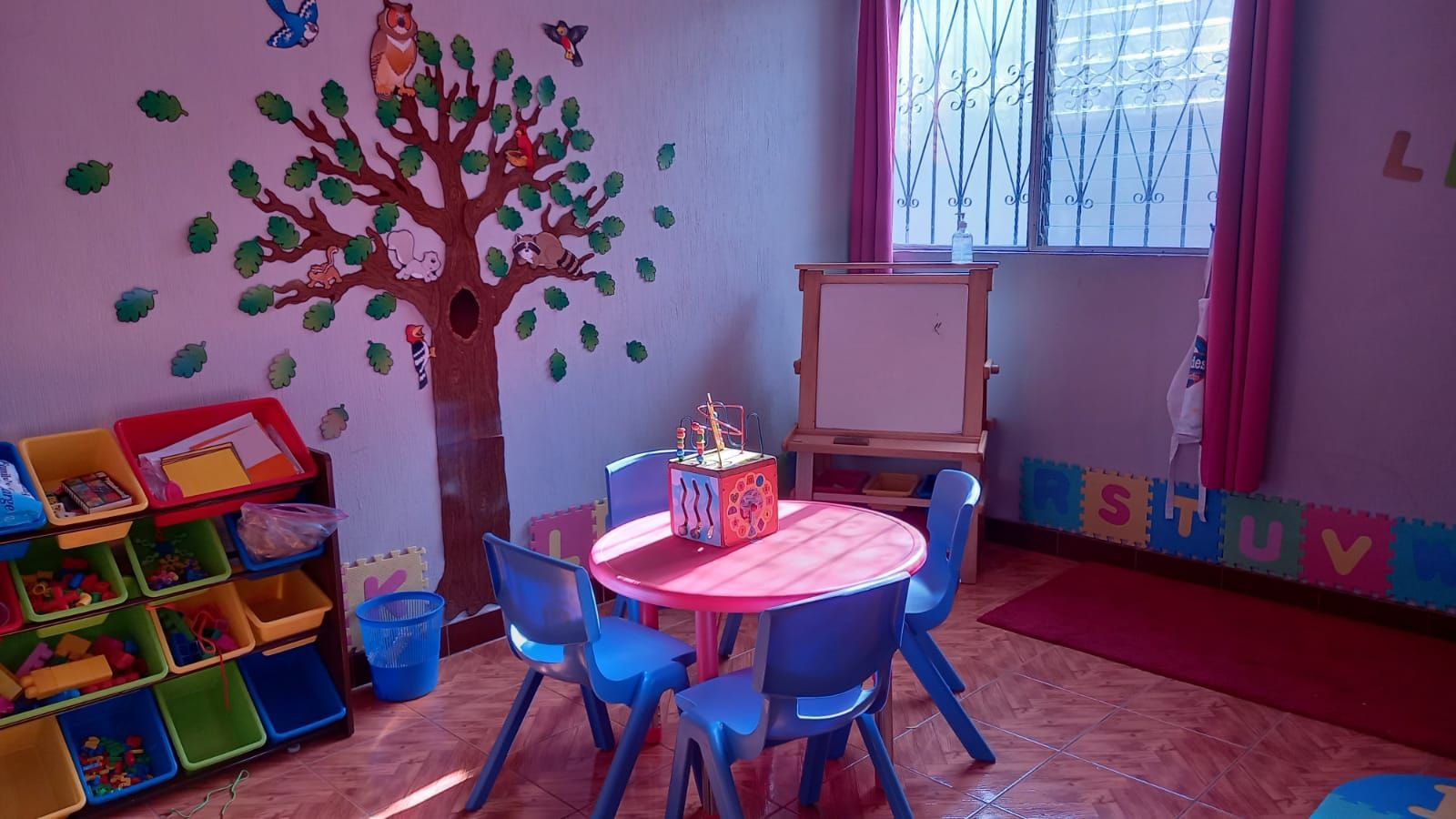 Un aula con mesas y sillas frente a una ventana.