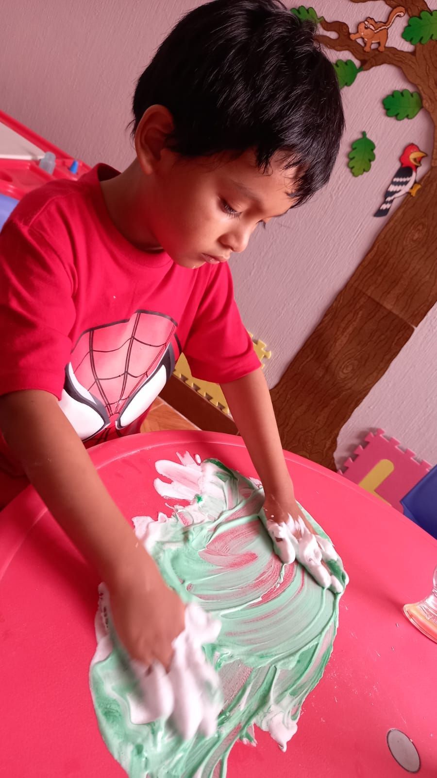Un niño pequeño está jugando con crema de afeitar en una mesa.