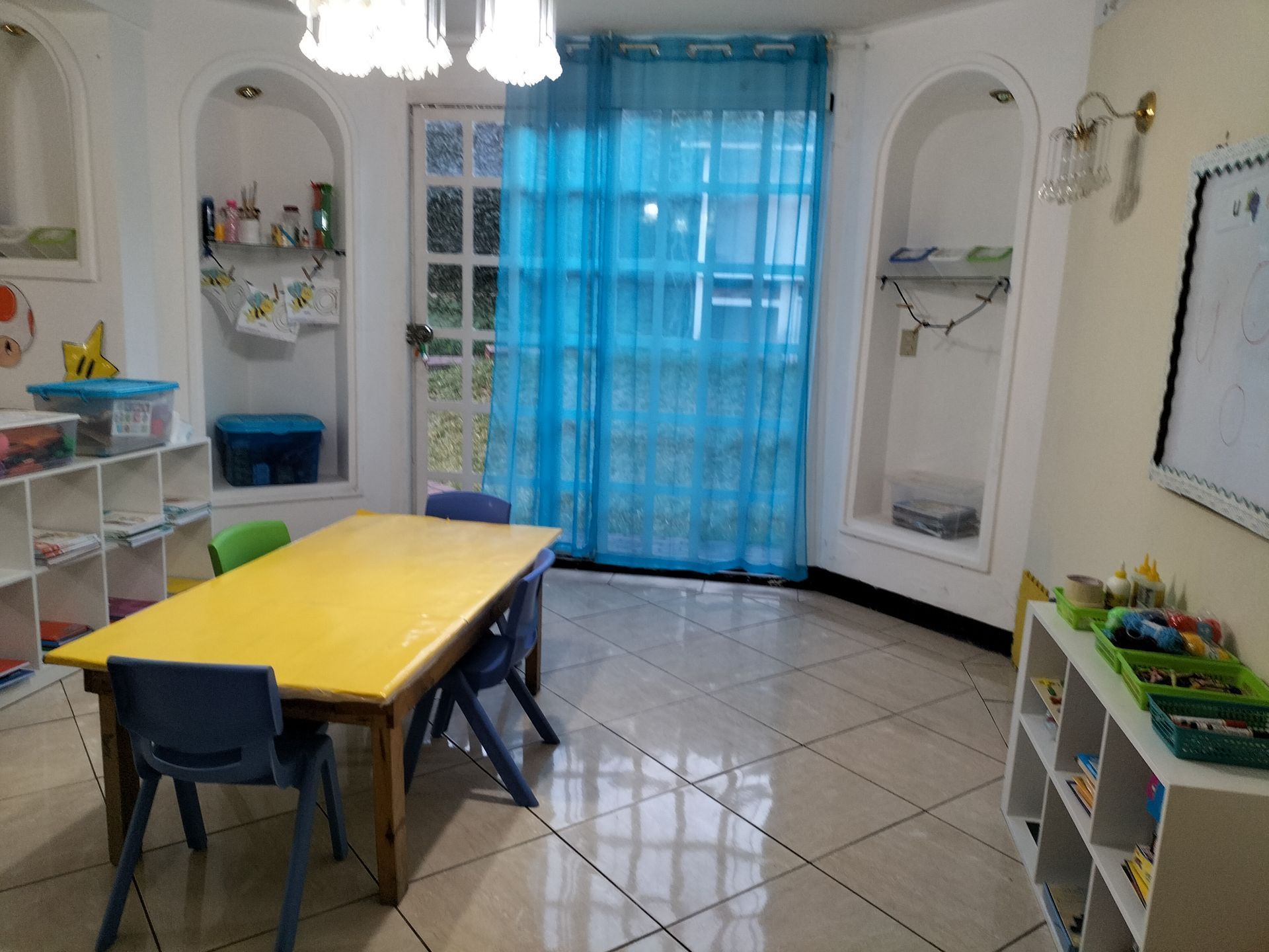 Una habitación con una mesa amarilla y sillas azules.