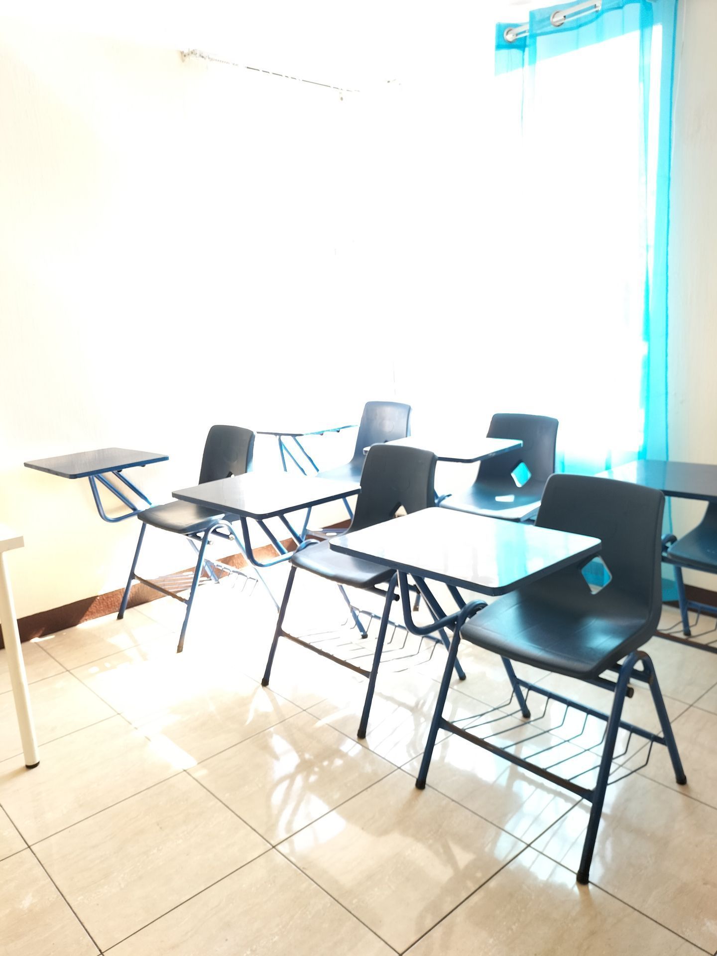 Un aula con mesas y sillas frente a una ventana.