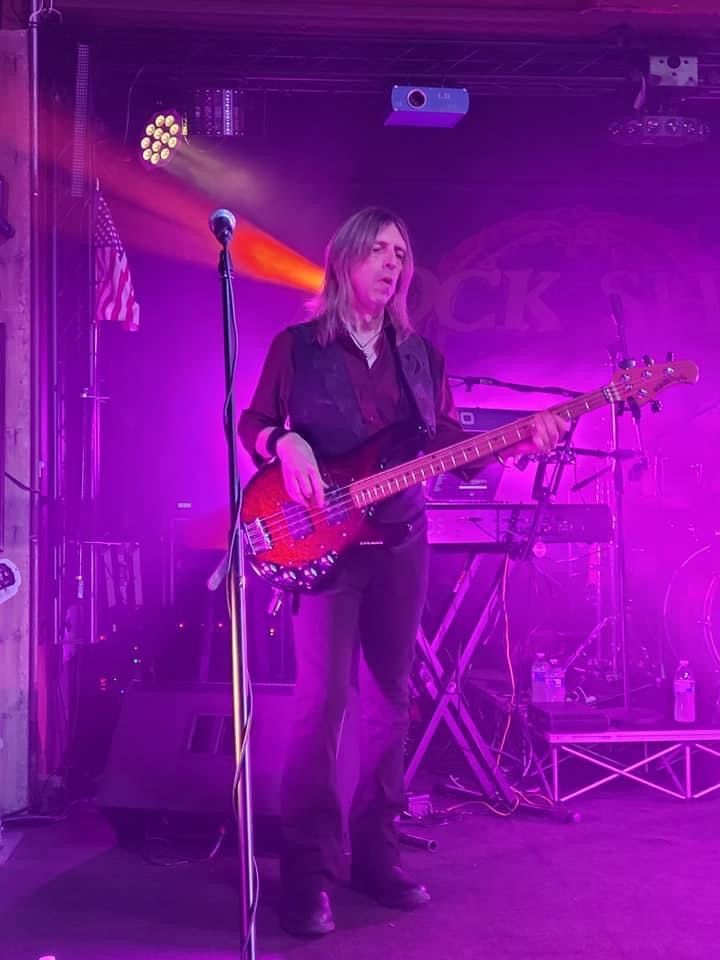 A man is playing a guitar on a stage in front of a microphone.