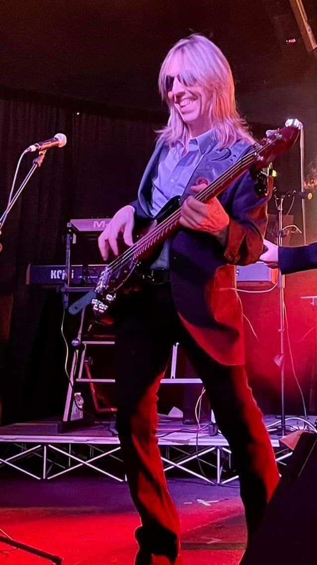 A man with long hair is playing a guitar on a stage.