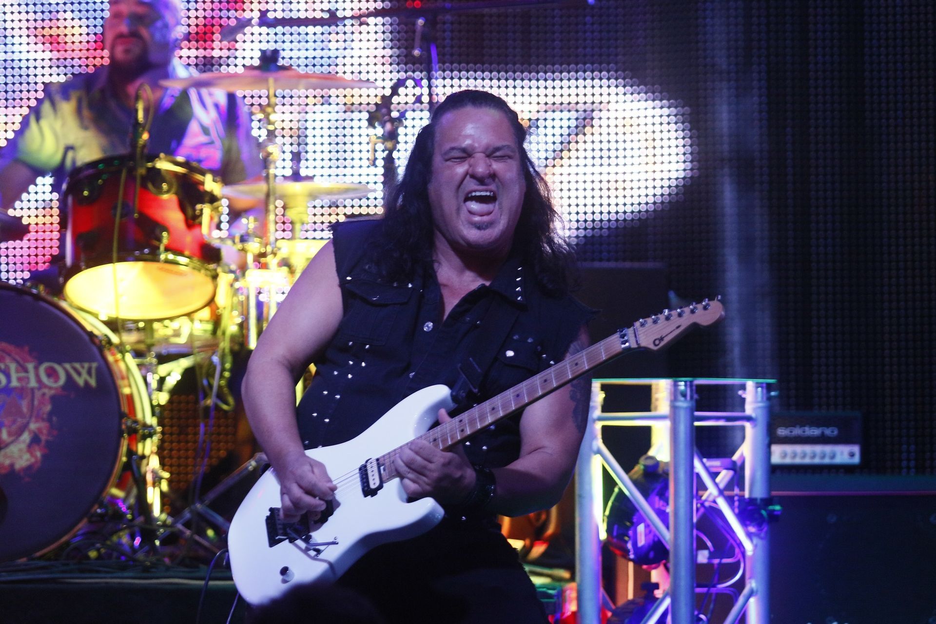 A man with long hair is playing a guitar on stage