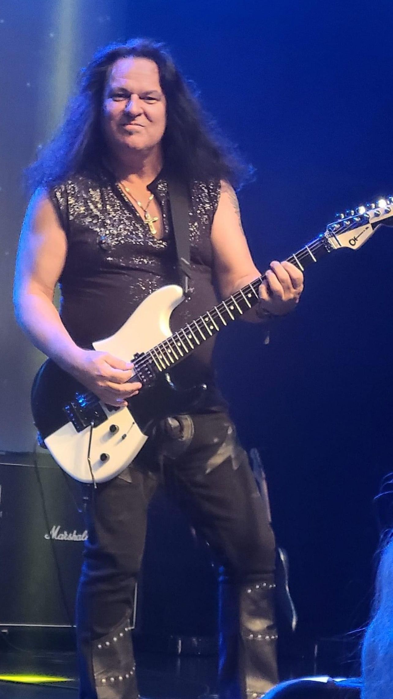 A man with long hair is playing a guitar on a stage.
