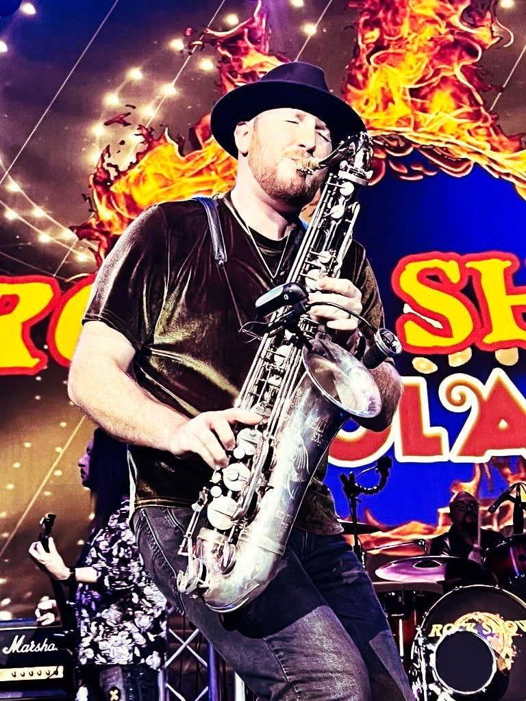 A man in a hat is playing a saxophone on a stage.