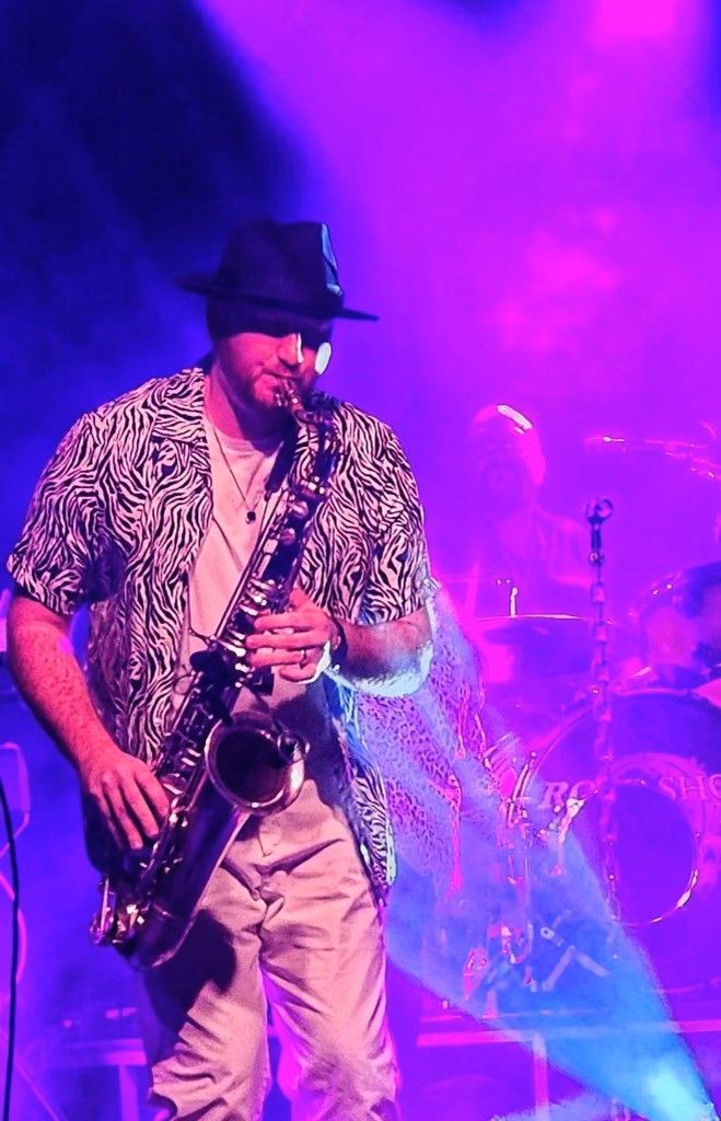 A man in a hat is playing a saxophone on a stage.