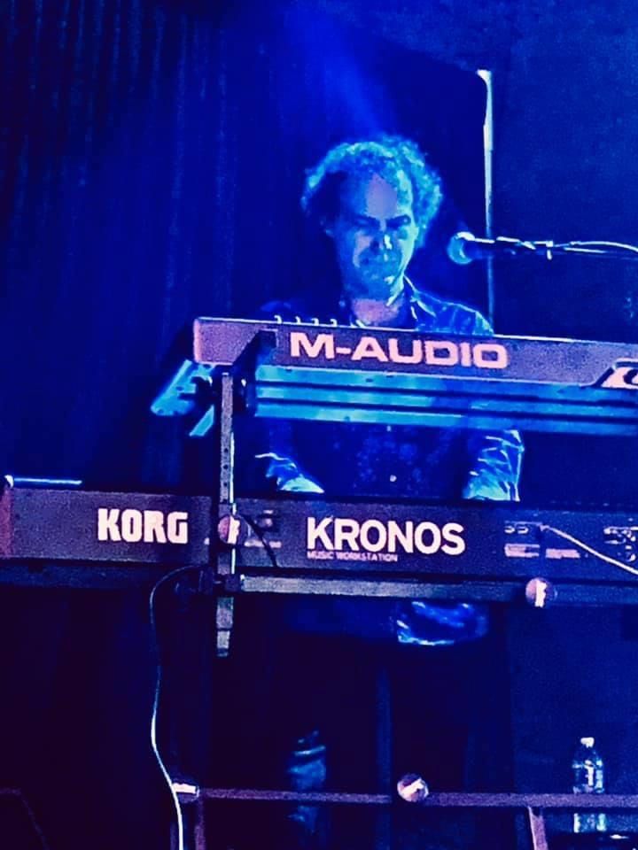 A man is playing a korg kronos keyboard on stage