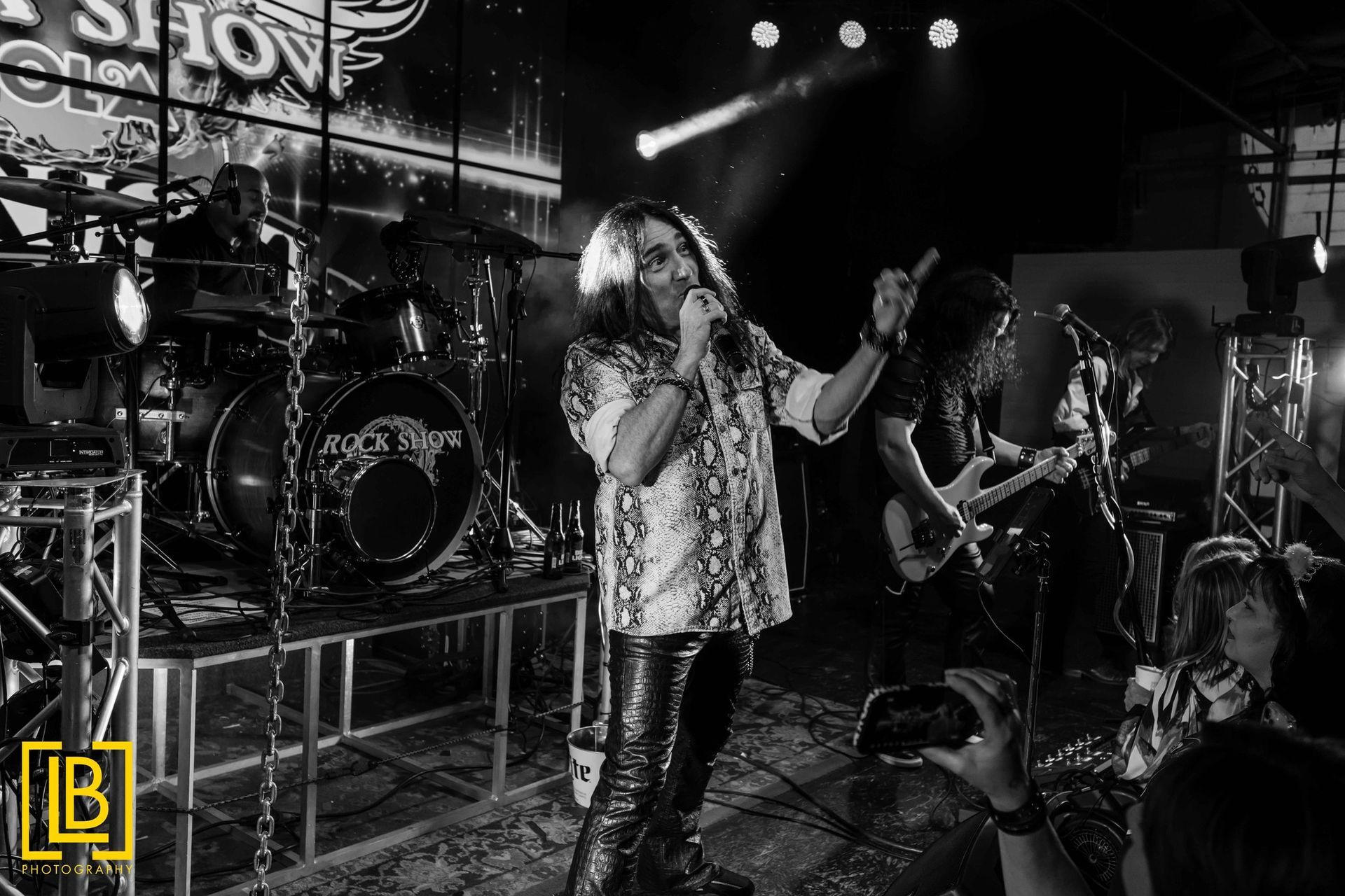 A black and white photo of a man singing into a microphone on a stage.