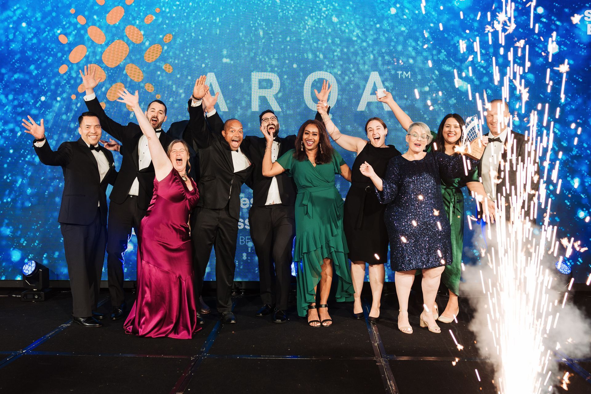 A group of people are standing on a stage with their arms in the air.