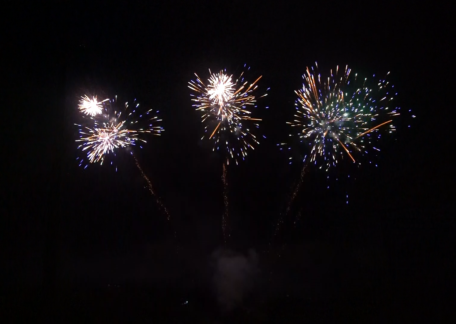 Four fireworks are exploding in the night sky