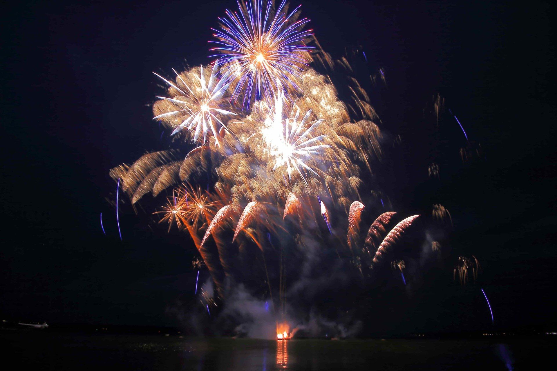 A fireworks display over a body of water at night