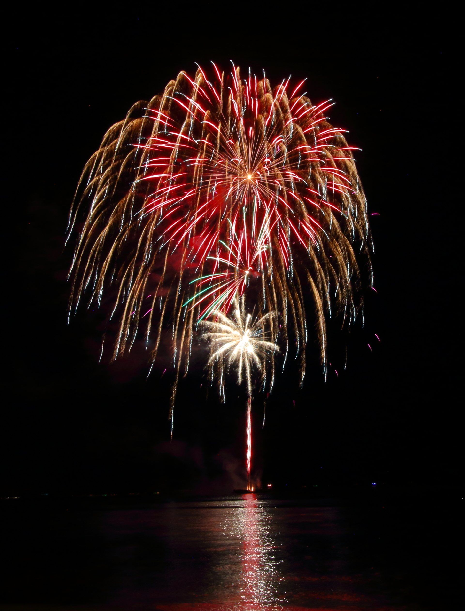 A fireworks display over a body of water at night