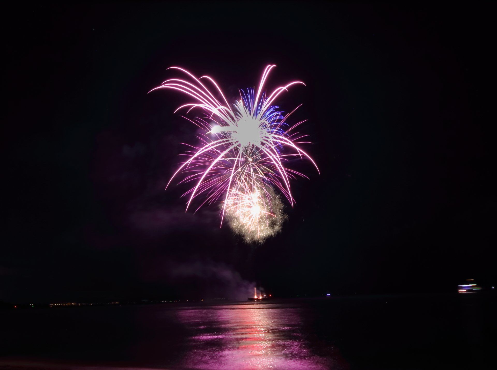 A fireworks display over a body of water at night.