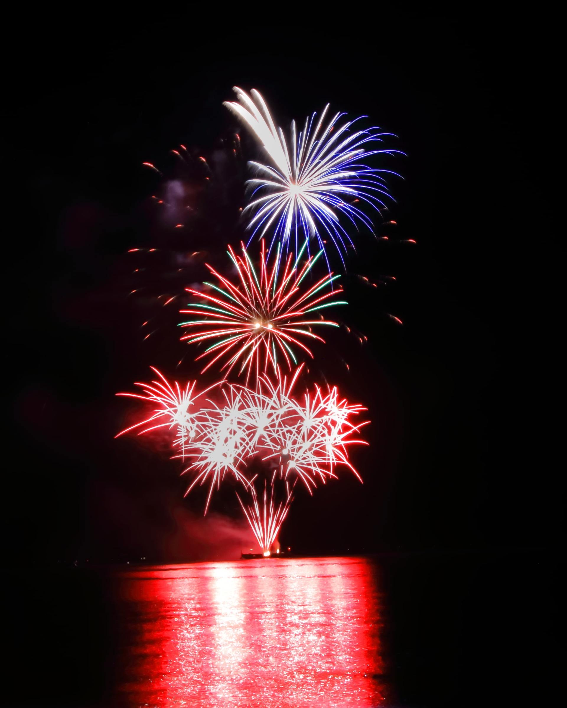 A bunch of fireworks are going off over a body of water