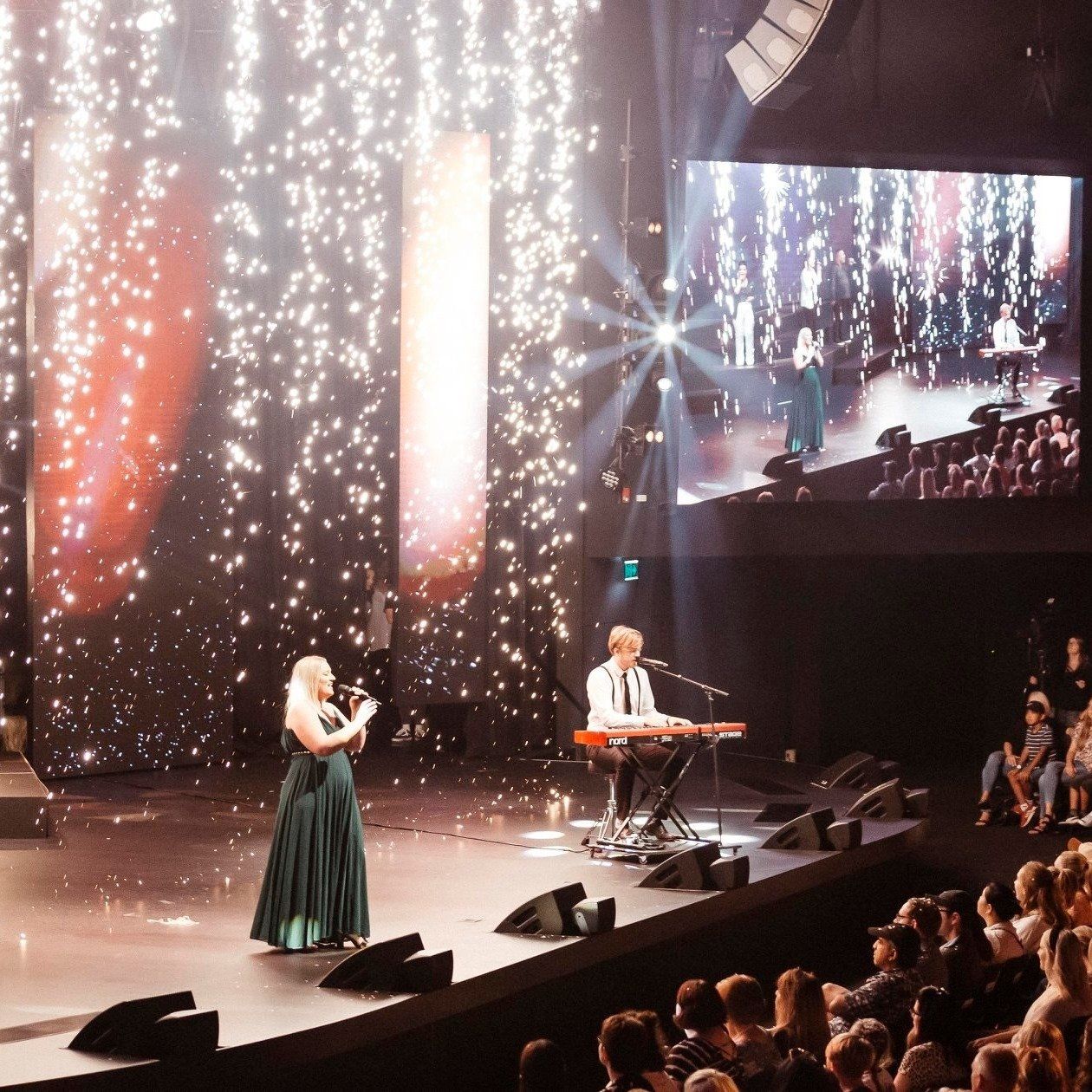A man playing a keyboard and a woman singing on a stage