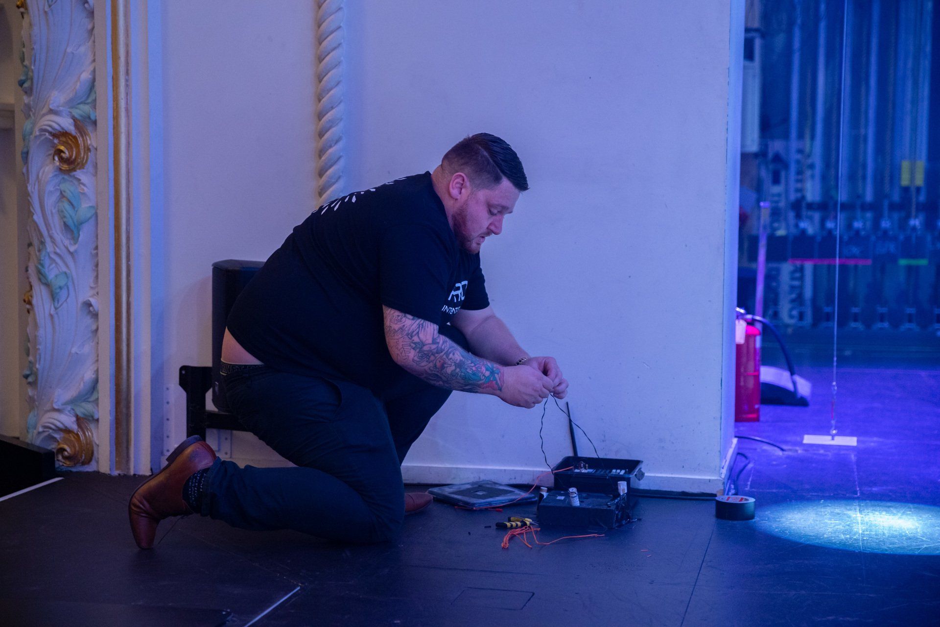 A man is kneeling on the floor working on a piece of equipment.