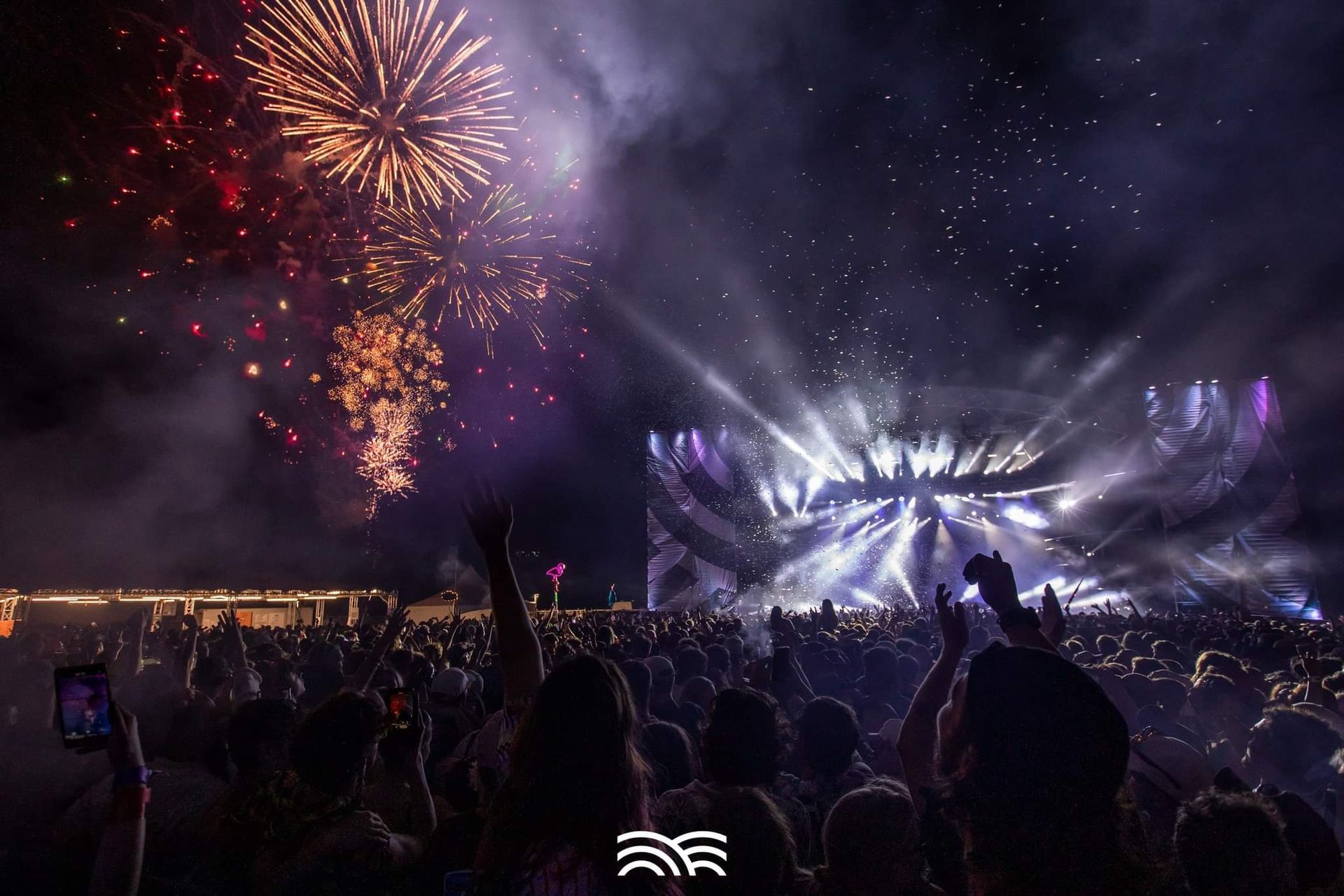 A crowd of people are watching fireworks at a concert.